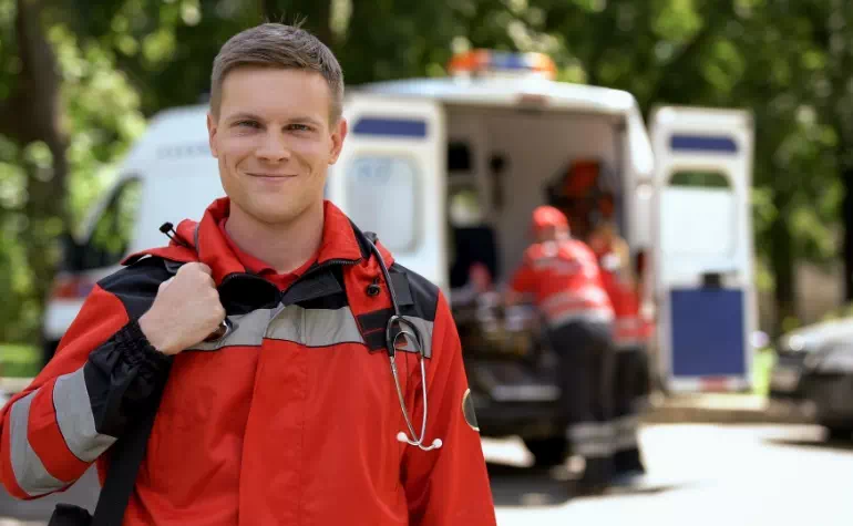 uśmiechnięty ratownik medyczny na tle ambulansu